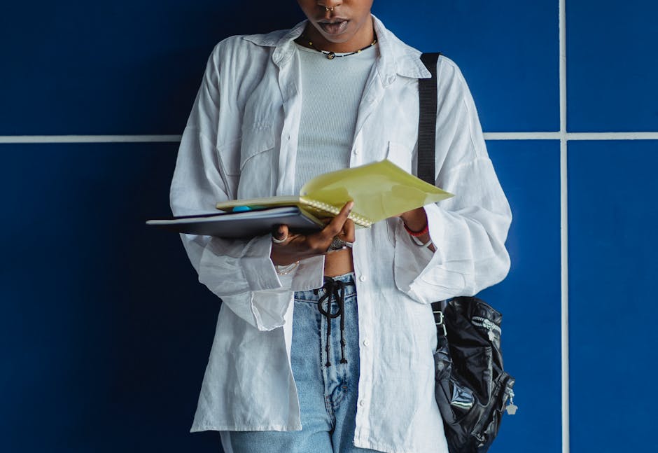 Crop anonymous ethnic woman in casual wear with rucksack watching exercise book near blue wall